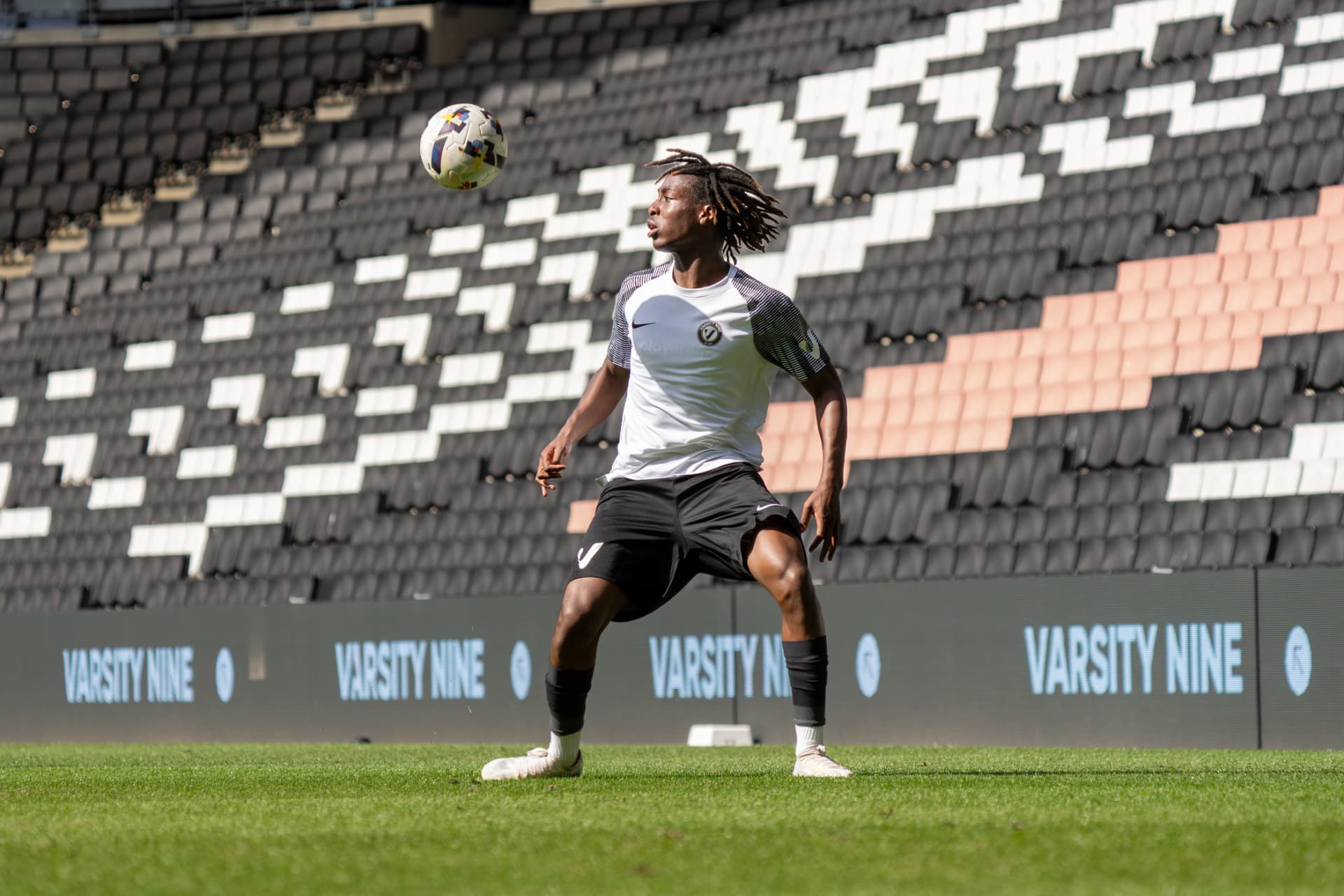 Player taking a first touch out of the air inside Stadium MK